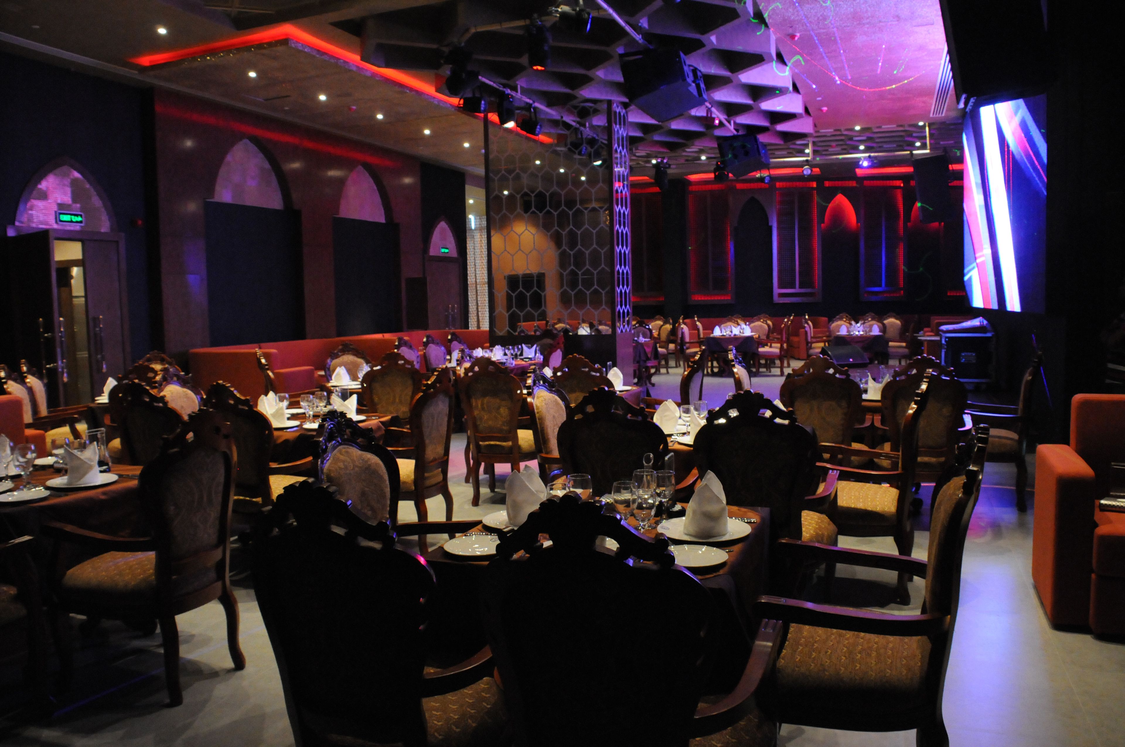 Un restaurant doté de nombreuses tables et chaises, d’une scène et d’un décor intérieur moderne.