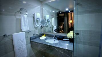 Une salle de bain moderne avec un lavabo en marbre, deux urinoirs, un porte-serviettes et un grand miroir.