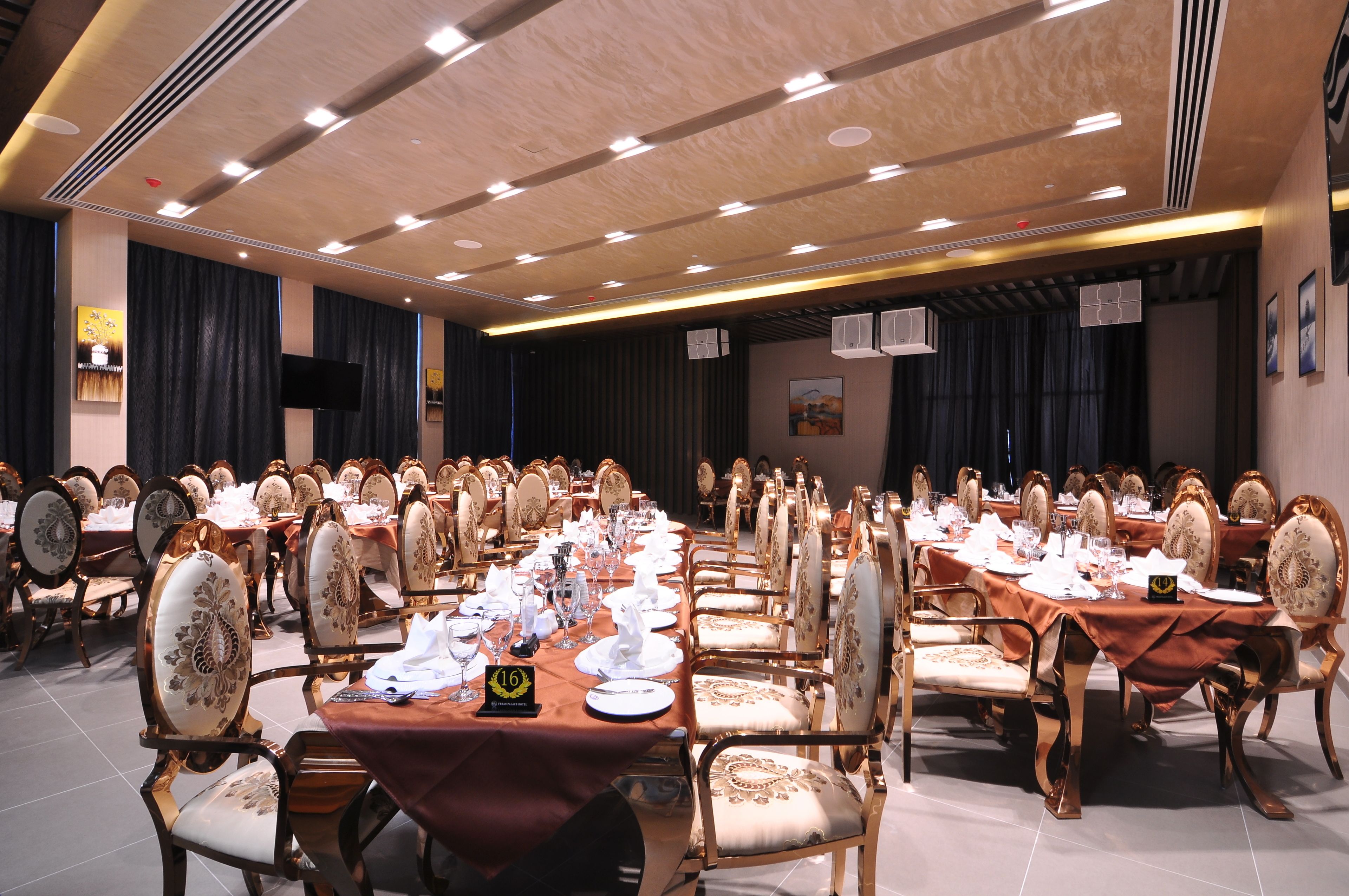 Uma sala de banquetes com várias mesas redondas, cada uma com toalhas brancas, pratos e copos.