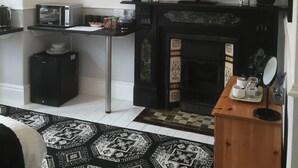 A modern living room with a fireplace, a flat-screen TV, a coffee machine, and decorative items. - Garswood Guesthouse (Penzance)
