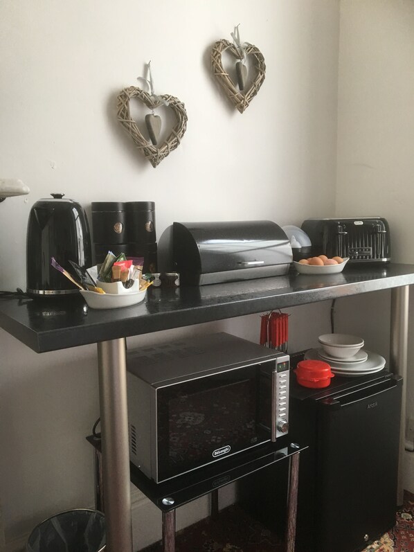 A kitchenette with a coffee maker, toaster, microwave, and a small refrigerator.