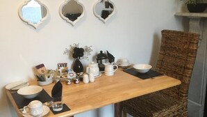 A dining area with a wooden table, two wicker chairs, and a decorative mirror wall. - Garswood Guesthouse (Penzance)