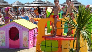 Eine Strandansicht mit bunten Spielgeräten und Strandsonnenschirmen.