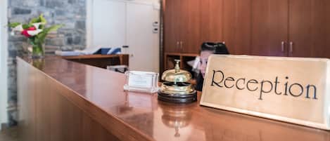 A reception desk with a wooden counter, a nameplate, a bell, and a small card.