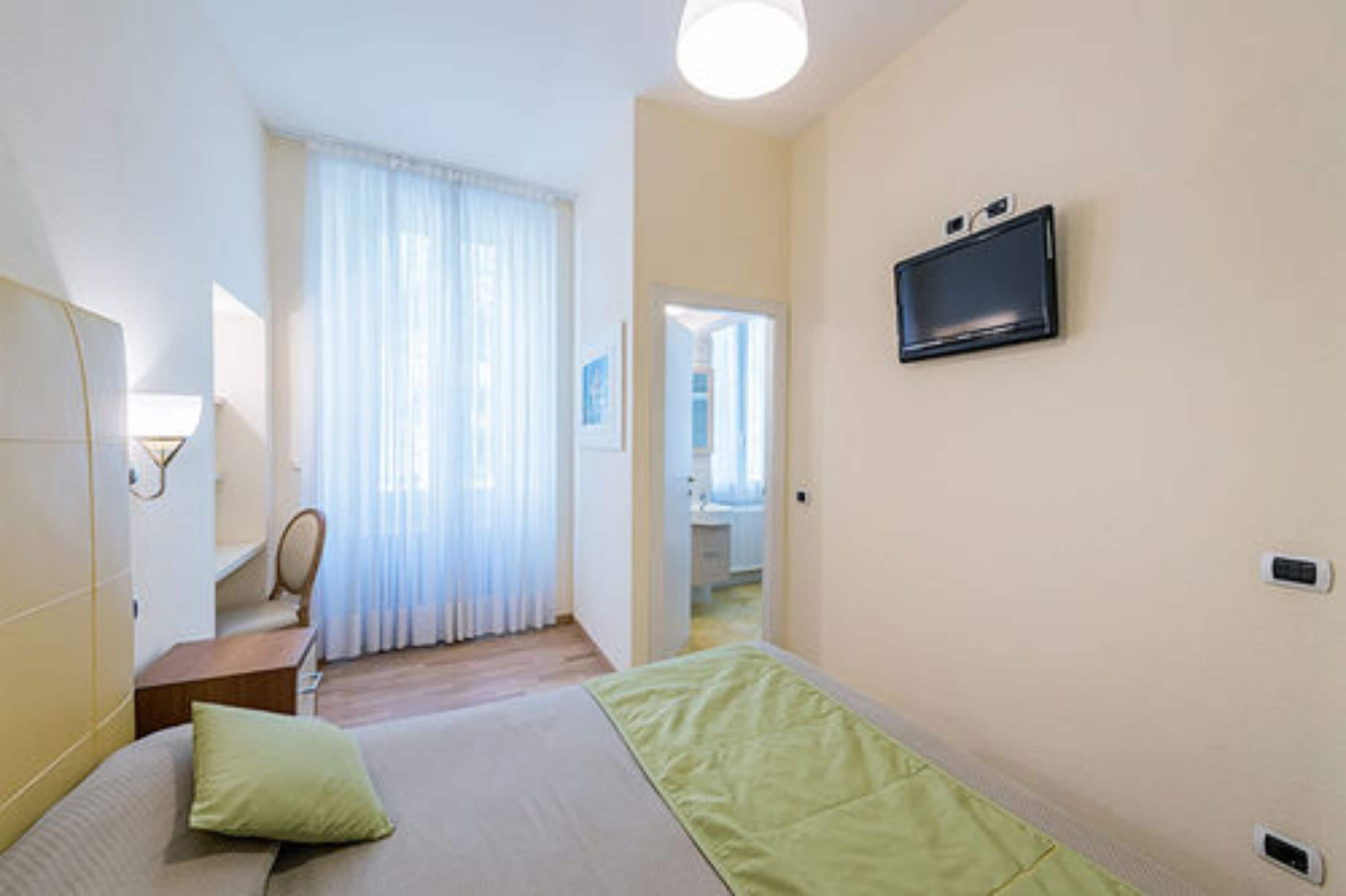 Une chambre d’hôtel équipée d’un lit, d’un téléviseur fixé au mur, d’un bureau et d’une chaise.
