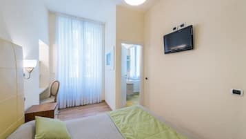 A hotel room with a bed, a TV mounted on the wall, a desk, and a chair.