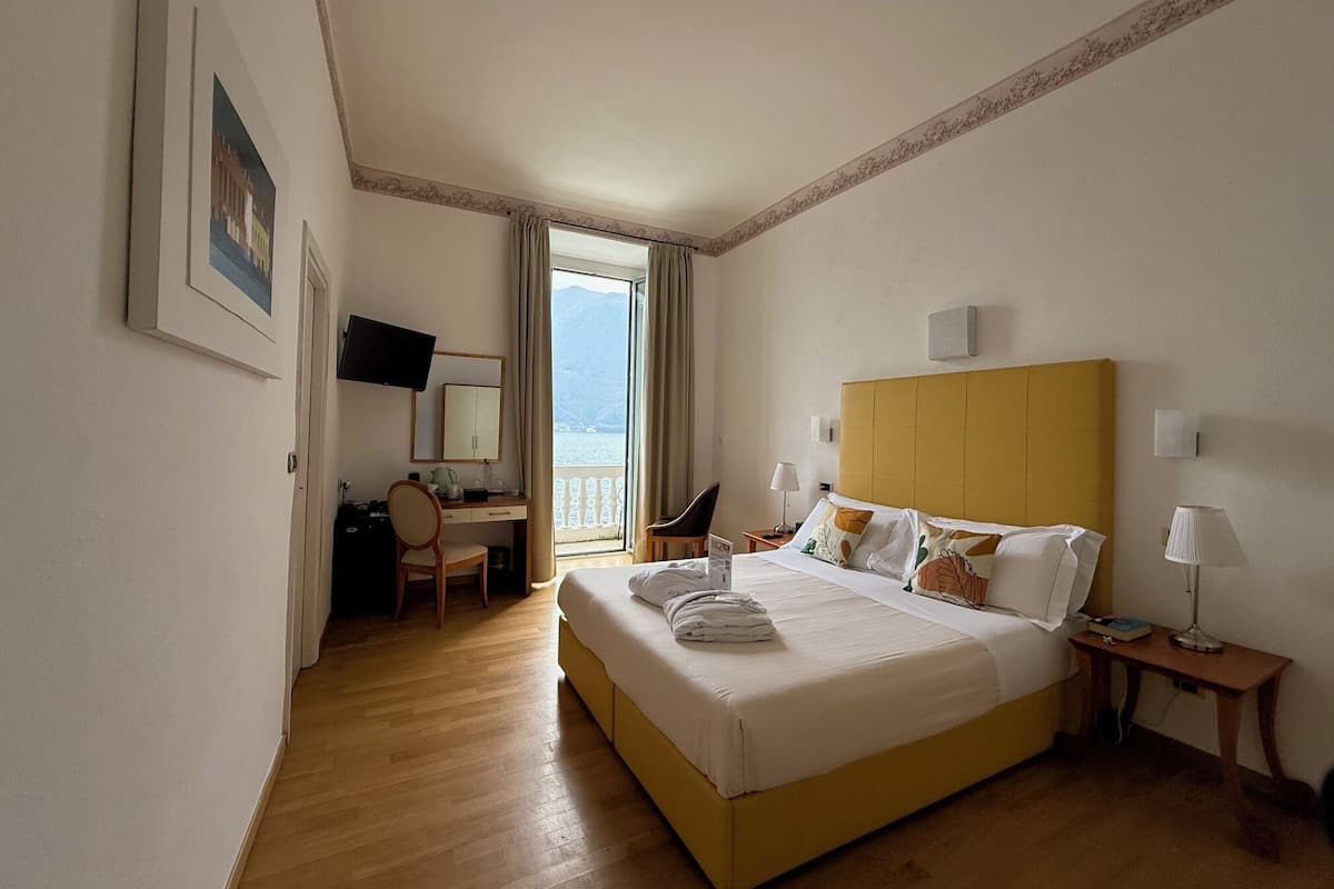 Une chambre d’hôtel avec un lit, un bureau, une chaise, une télévision et une vue sur la mer.