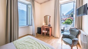 Habitación de hotel con cama, escritorio, silla, televisión y vistas al mar.