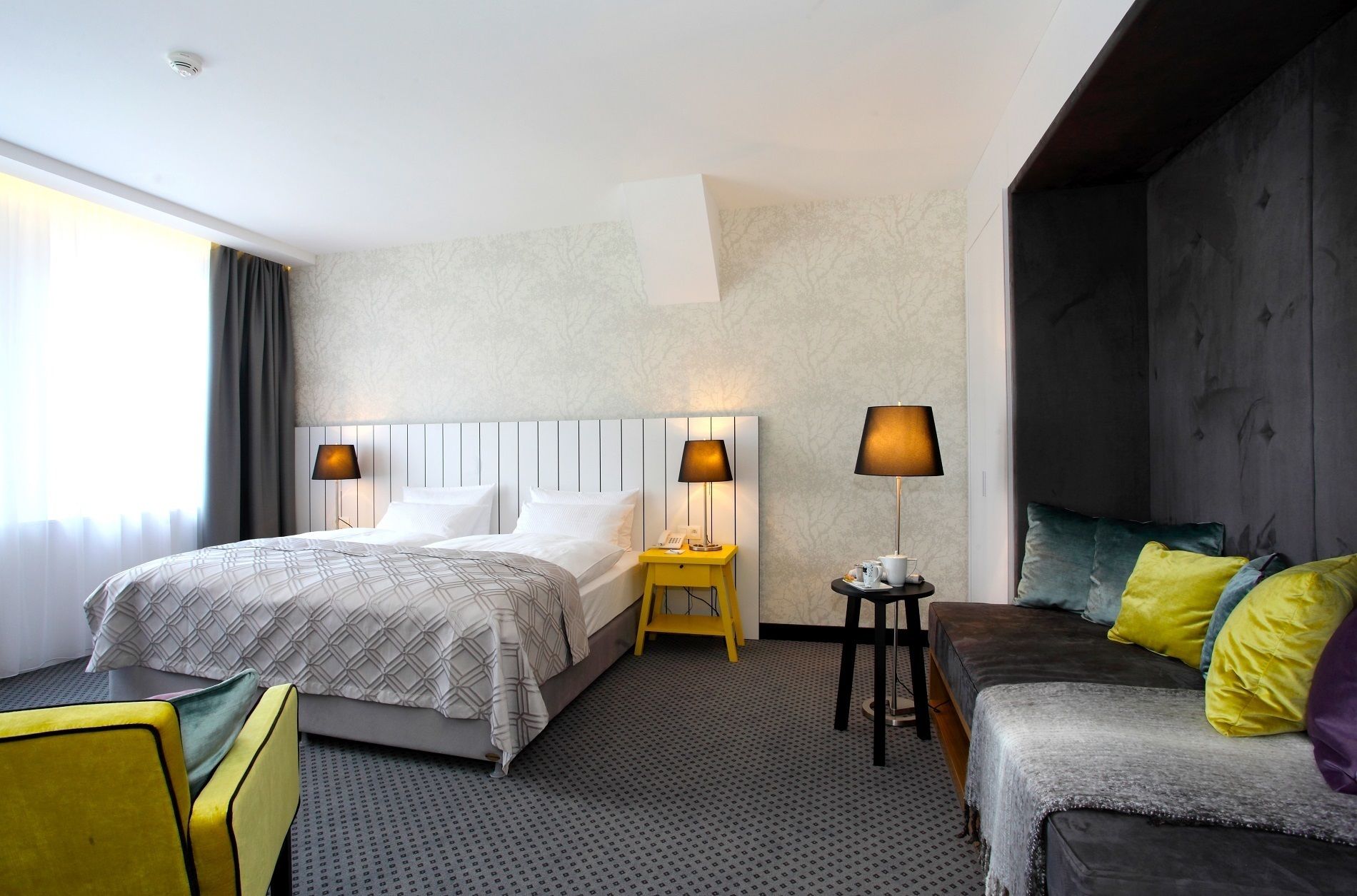 Habitación de hotel con dos camas, un sofá y una mesita con lámparas.