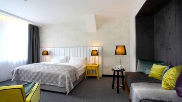 Habitación de hotel con dos camas, un sofá y una mesita con lámparas.