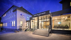 A hotel with a modern facade, a visible entrance with a staircase, and a sign indicating a 4-star rating. - Hotel Pod Lipou (Modra)