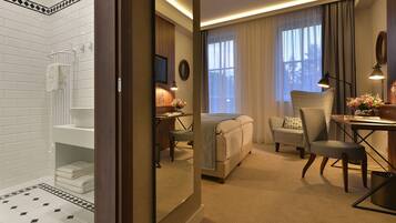 Una habitación de hotel con baño, cama, escritorio, silla y televisor.