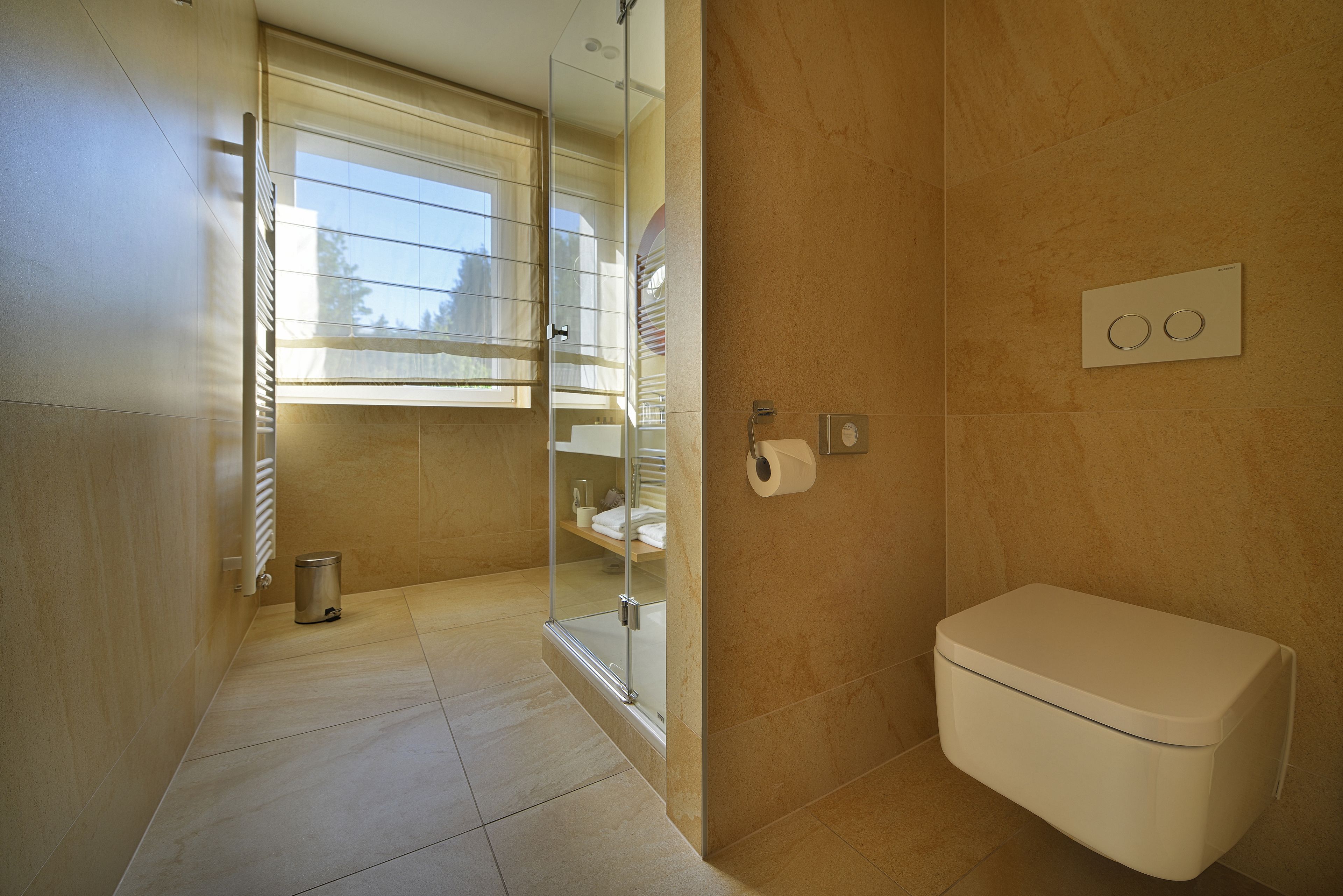 Une salle de bain moderne équipée de toilettes, d’une douche à parois de verre et d’un porte-serviettes.