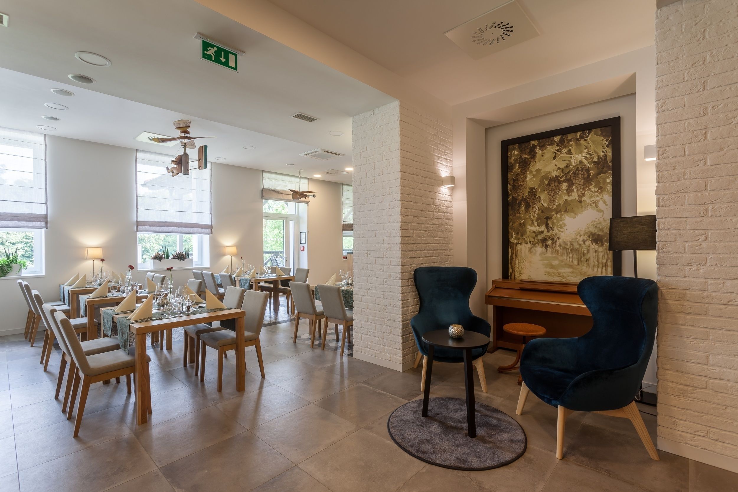 Uma sala de jantar com mesas e cadeiras, um piano e um grande quadro abstrato na parede.