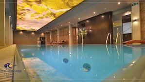 A modern indoor swimming pool with clear water, lounge chairs, and a ceiling with a leaf pattern. - Hotel Pod Lipou (Modra)