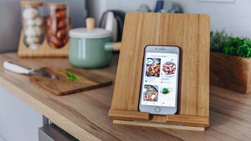Ein Smartphone auf einem Holzständer, das eine Rezept-App anzeigt.