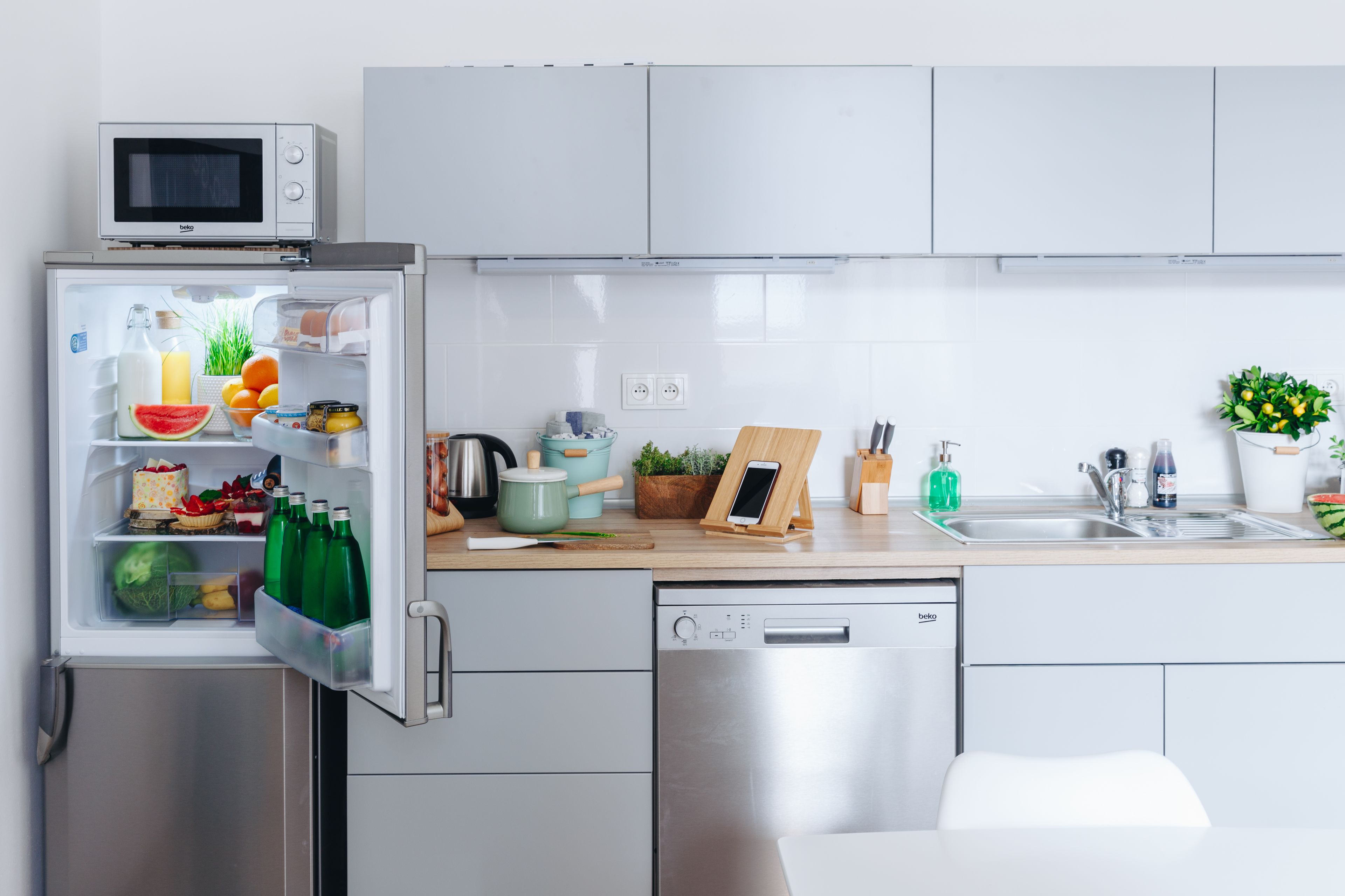 Una cocina moderna con microondas incorporado, lavavajillas y refrigerador lleno de provisiones.