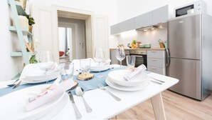 A modern kitchen with stainless steel appliances, a dining table set with white plates, glasses, and cutlery. - CHILL Apartments (Prague)