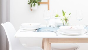 A dining area with a white table set for two, a wooden ladder shelf with plants, and white chairs. - CHILL Apartments (Prague)