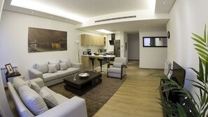 A modern living room with a sofa set, a coffee table, and a dining area with a kitchen in the background. - Kantari Suites (Beirut)