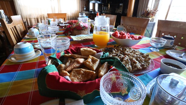 Et morgenbord dækket med forskellige spiser, herunder bagværk, frugt og drikkevarer.