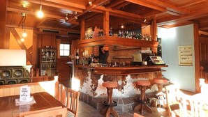 Eine Bar mit Holzbalken, einem Barkeeper und Hockern.