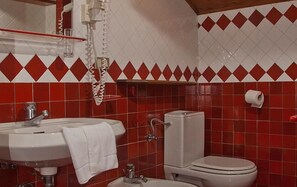 A bathroom with a white sink, toilet, and shower. The walls are tiled in red and white. - Resort Borgo al Sole and Spa (Sappada)