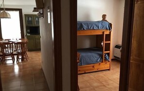 A room with a bunk bed, a dining table with chairs, and a kitchen area in the background. - Resort Borgo al Sole and Spa (Sappada)