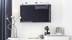 A modern, white desk with a flat-screen TV, a coffee maker, and a cup. A chair is positioned in front of the desk. - M2M Made To Measure (Milan)