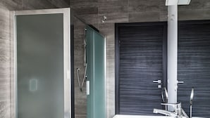 A modern bathroom with a glass-enclosed shower, a large white sink, and a dark-toned door. - M2M Made To Measure (Milan)