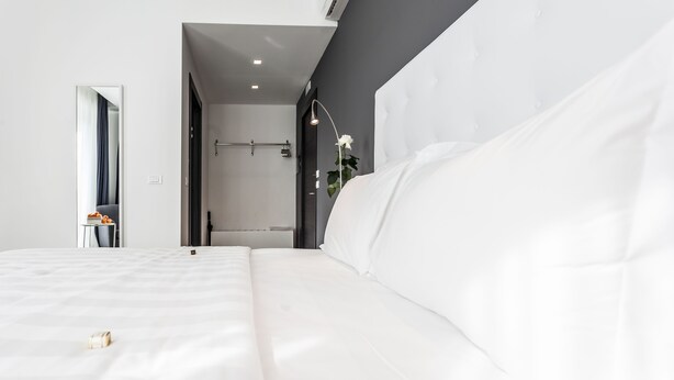 A modern hotel room with a large bed, a mirror, and a shower area. - M2M Made To Measure (Milan)