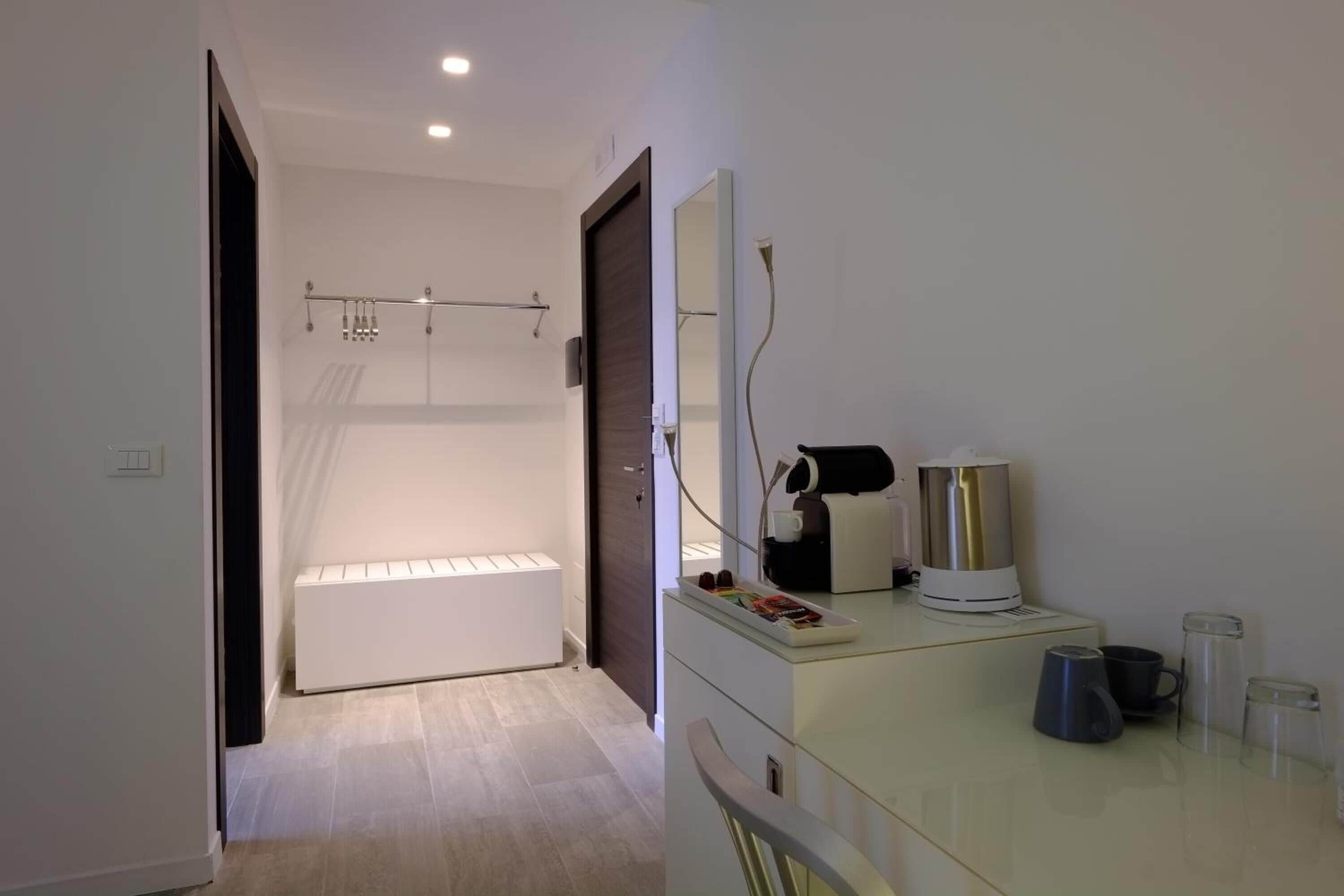 Une salle de bain moderne avec une douche à parois de verre, un radiateur blanc et un meuble-lavabo doté d’un miroir et d’une machine à café.