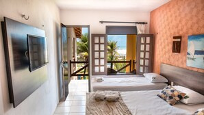 Een hotelkamer met twee bedden, een televisie en uitzicht op het strand.
