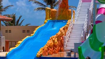 Un tobogán de agua con diseño rocoso, una escalera y una zona de piscina.