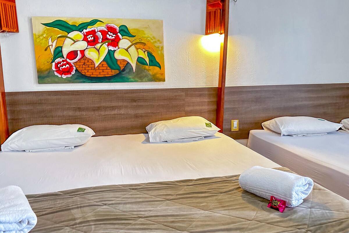 A hotel room with two beds, a painting of flowers on the wall, and a night light.