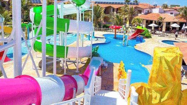 Een waterpark met glijbanen en zwembaden, omringd door palmbomen en gebouwen.