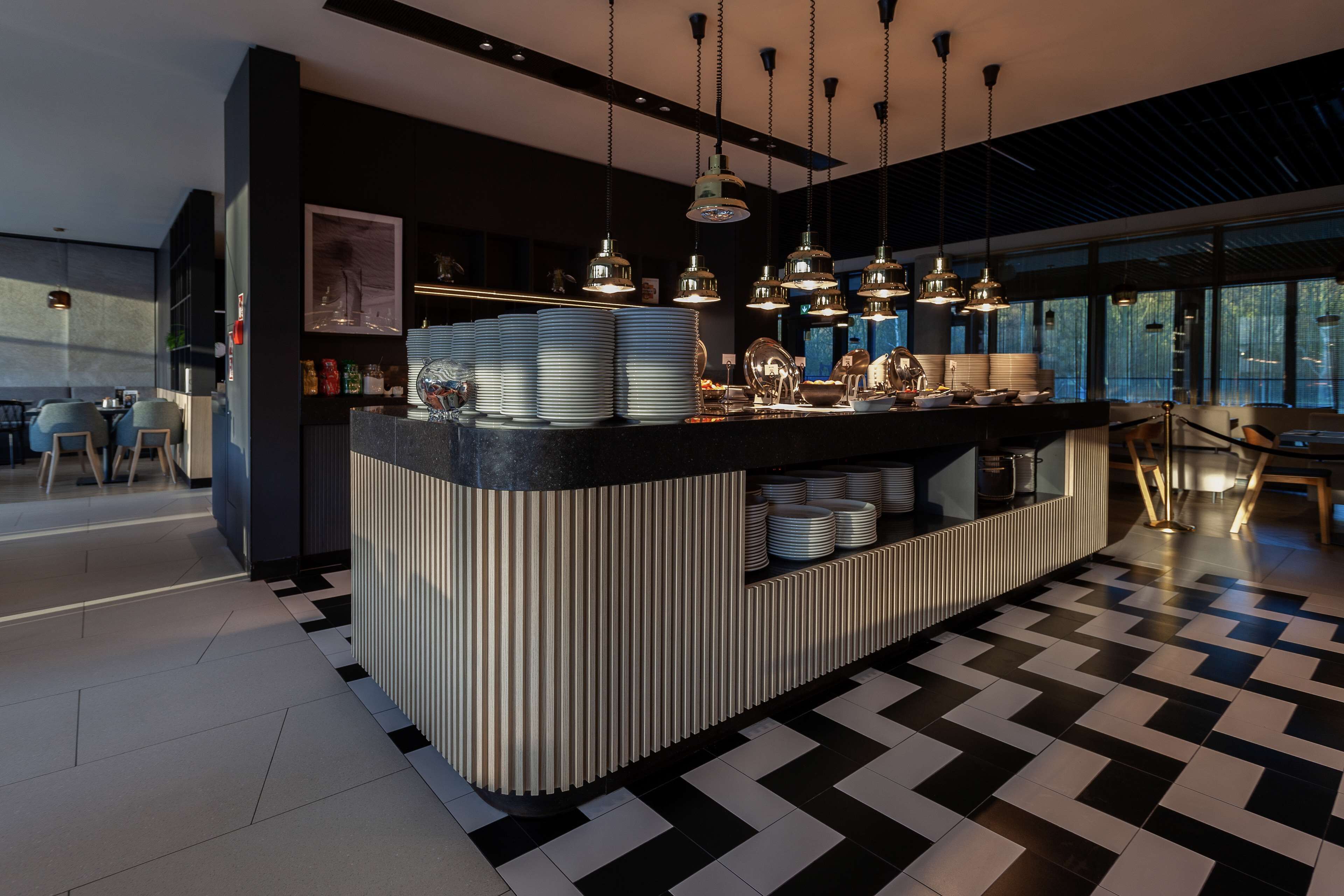 A modern bar area with a central counter, hanging pendant lights, and a checkered floor pattern.