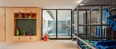 A room with a play area, a large window, and a wooden cabinet with toys.