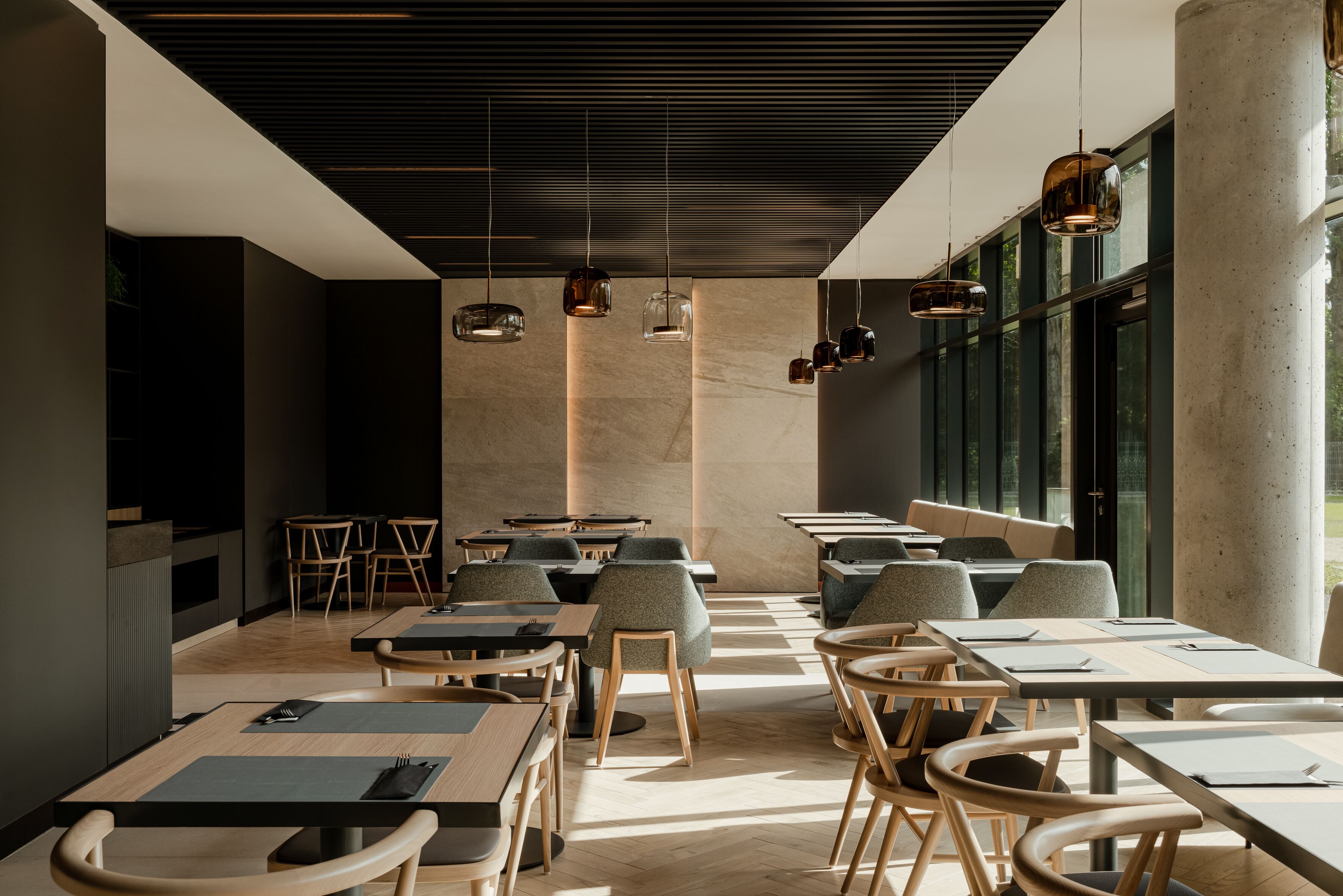 Interior moderno de restaurante com mesas altas, cadeiras e luminárias pendentes.