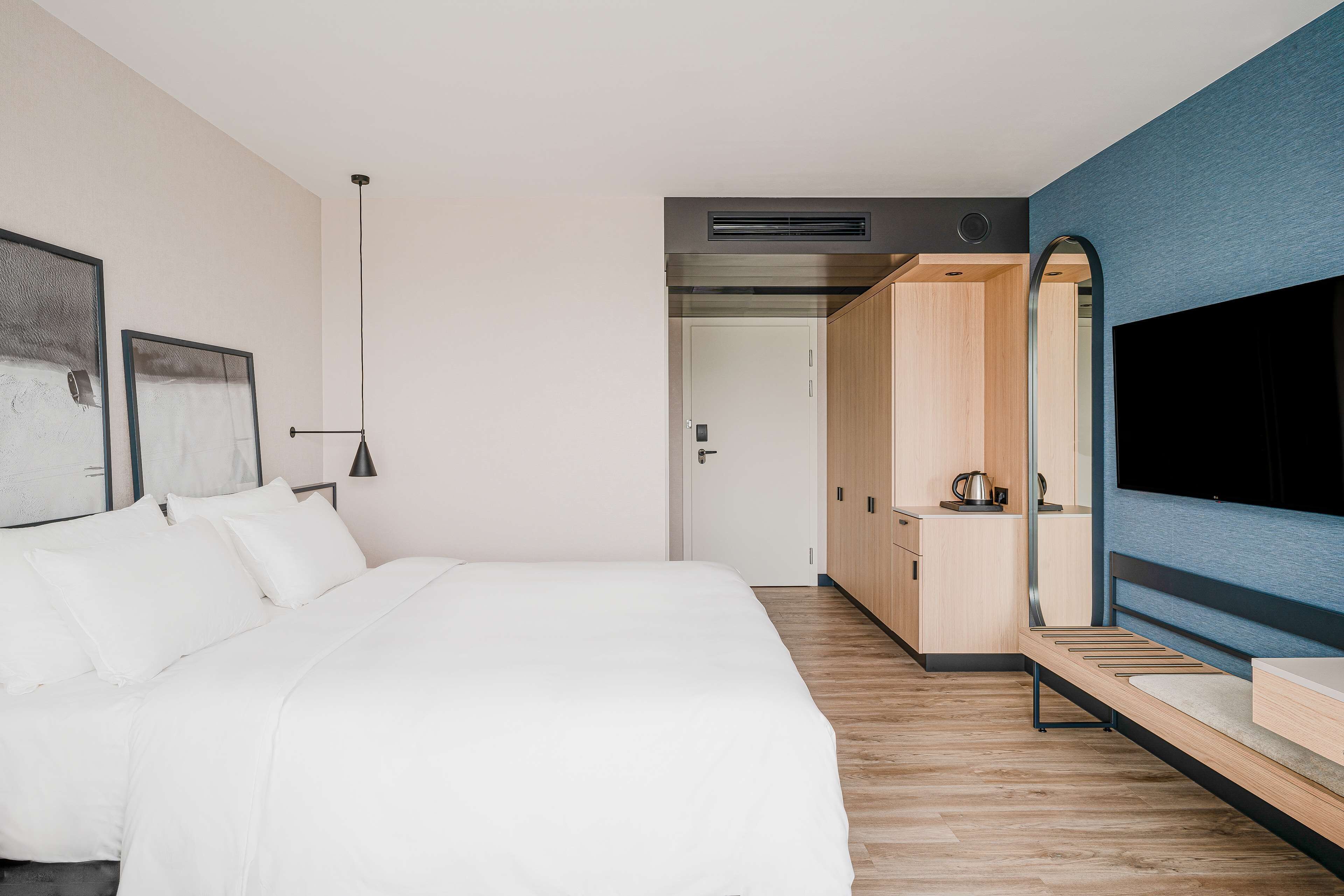 A modern bedroom with a large bed, a TV, and a wardrobe.