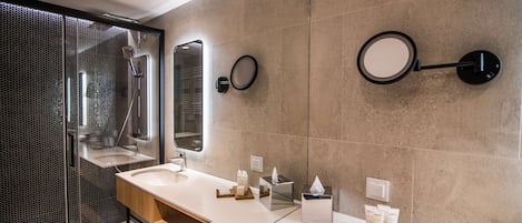 A modern bathroom with a glass shower enclosure, two sinks, and a large mirror.