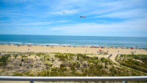 A beach with a clear sky, a plane flying overhead, and a view of the ocean. - Worcester House 503 by RedAwning (Ocean City)