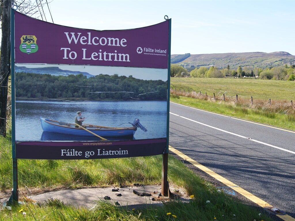 A welcome sign for Leitrim with a scenic background of a lake and mountains.