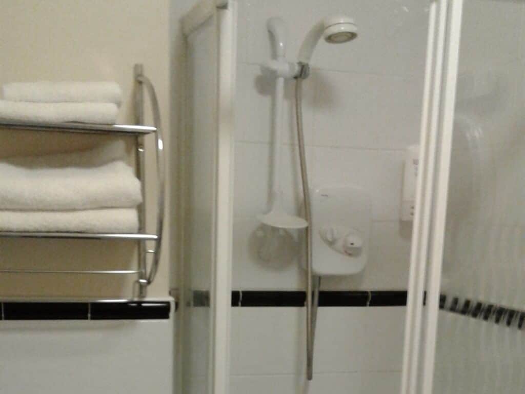 A bathroom with a shower, a towel rack, and a toilet.