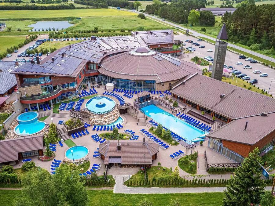 Un complexe hôtelier doté de plusieurs piscines, de chaises longues et d’un grand parking.