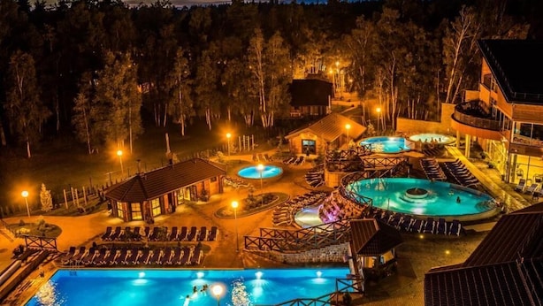 Un resort con varias piscinas, tumbonas y un pabellón cubierto.
