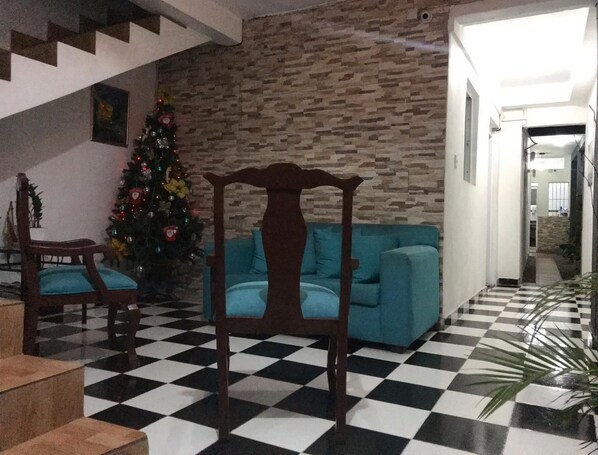 A living room with a checkered floor, a Christmas tree, and a teal sofa. - Aarony House (Santo Domingo)