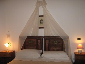 Una cama con dosel, dos mesitas de noche con lámparas y un reloj de pared.