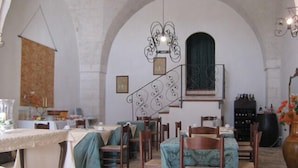 Un comedor con mesas y sillas, una escalera y una estantería para vinos.