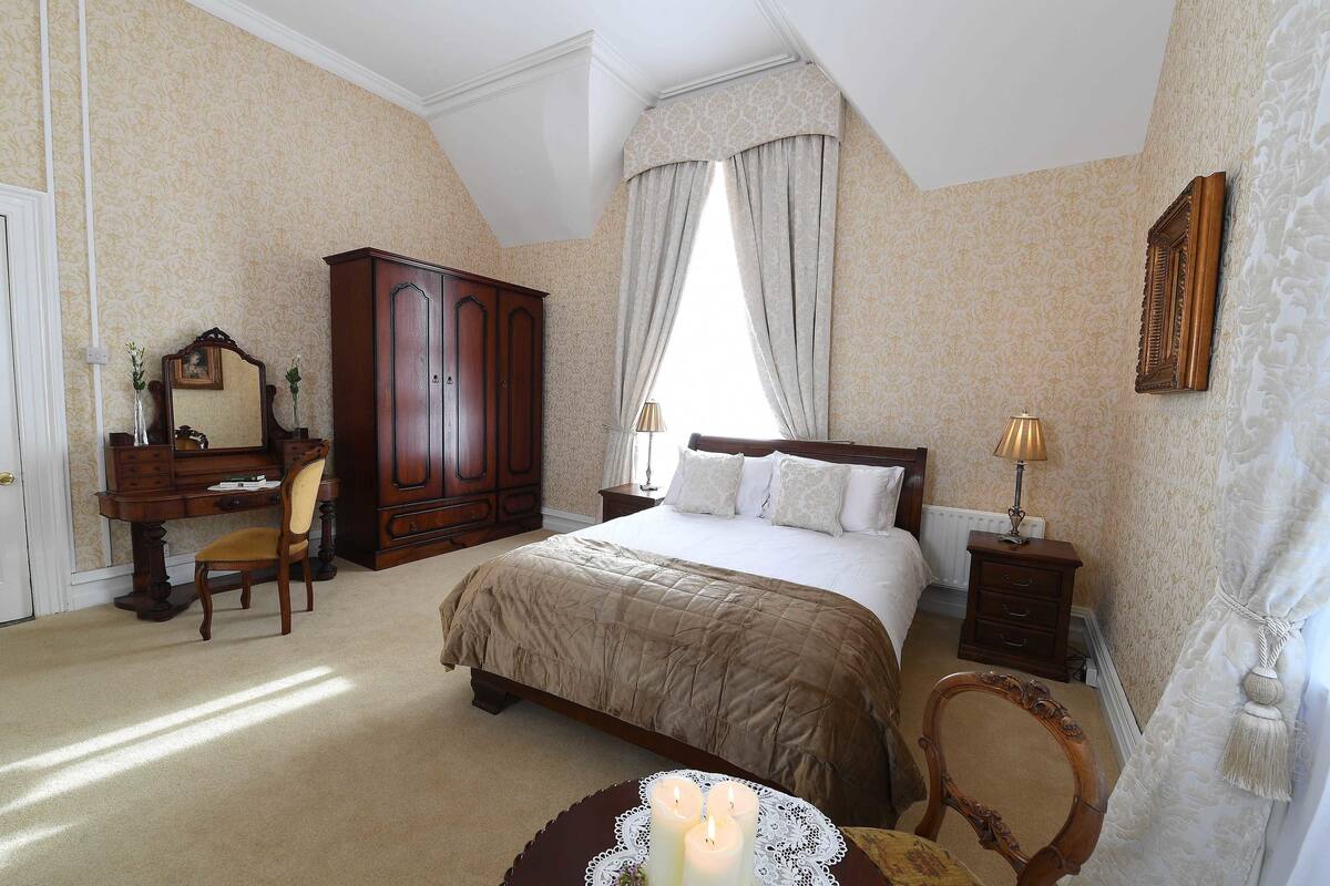 Un dormitorio con una cama grande, un aparador, un escritorio y una silla.